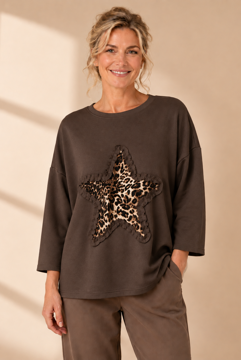 Vit oversize-tröja med leopardmönstrad stjärna och dekorativ volangdetalj framtill.
