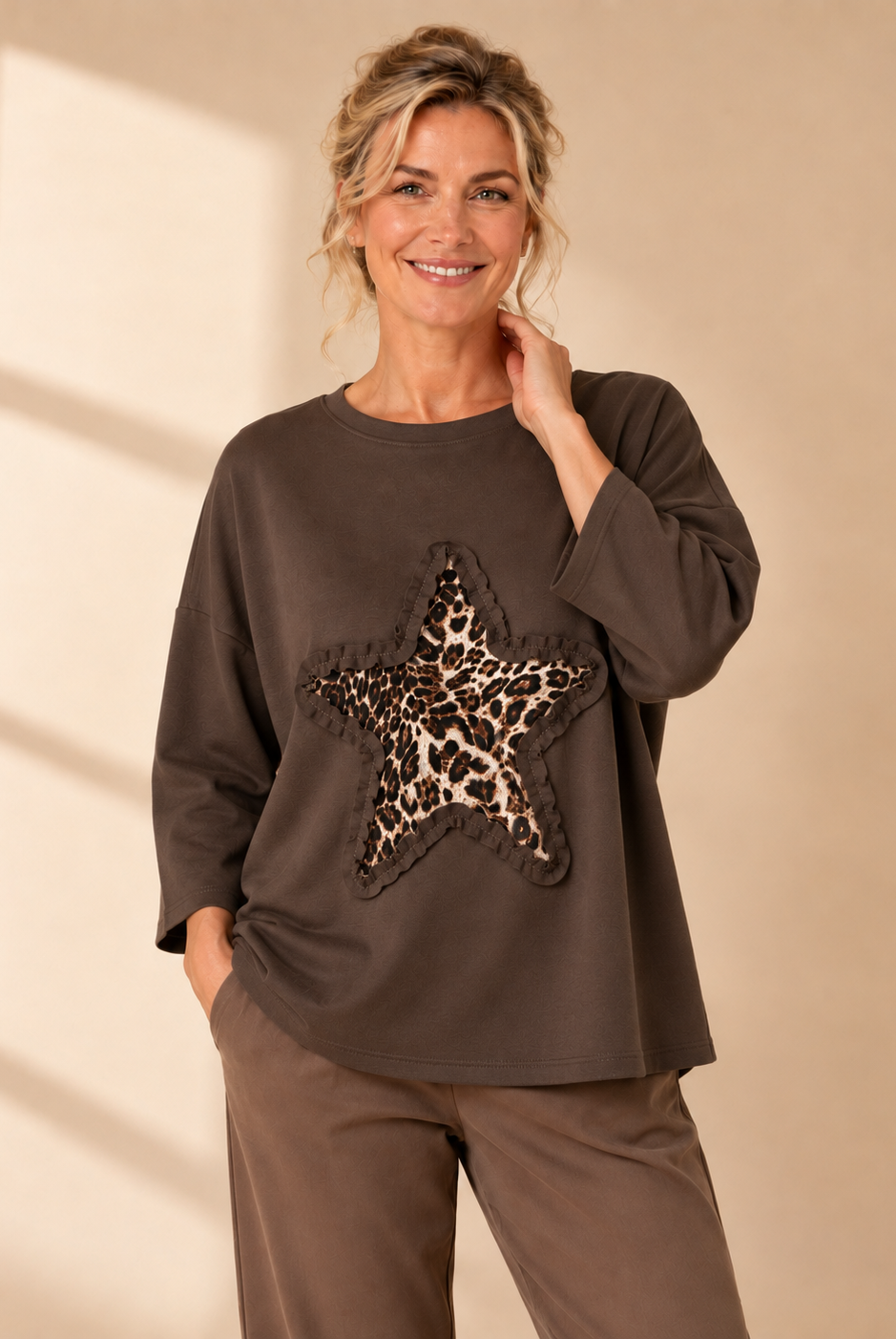 Vit oversize-tröja med leopardmönstrad stjärna och dekorativ volangdetalj framtill.