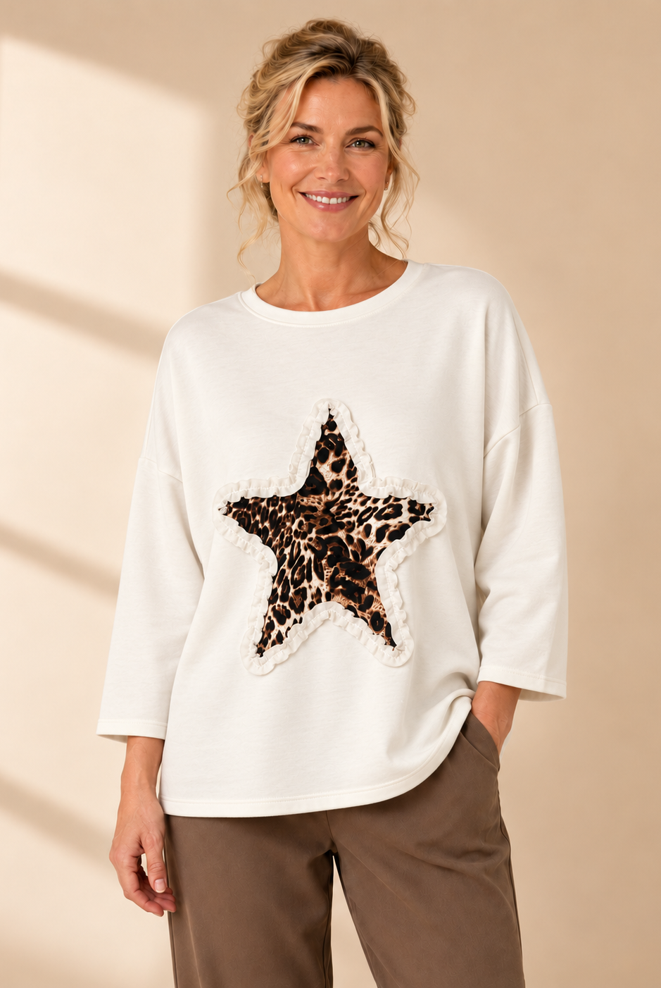 Vit oversize-tröja med leopardmönstrad stjärna och dekorativ volangdetalj framtill.