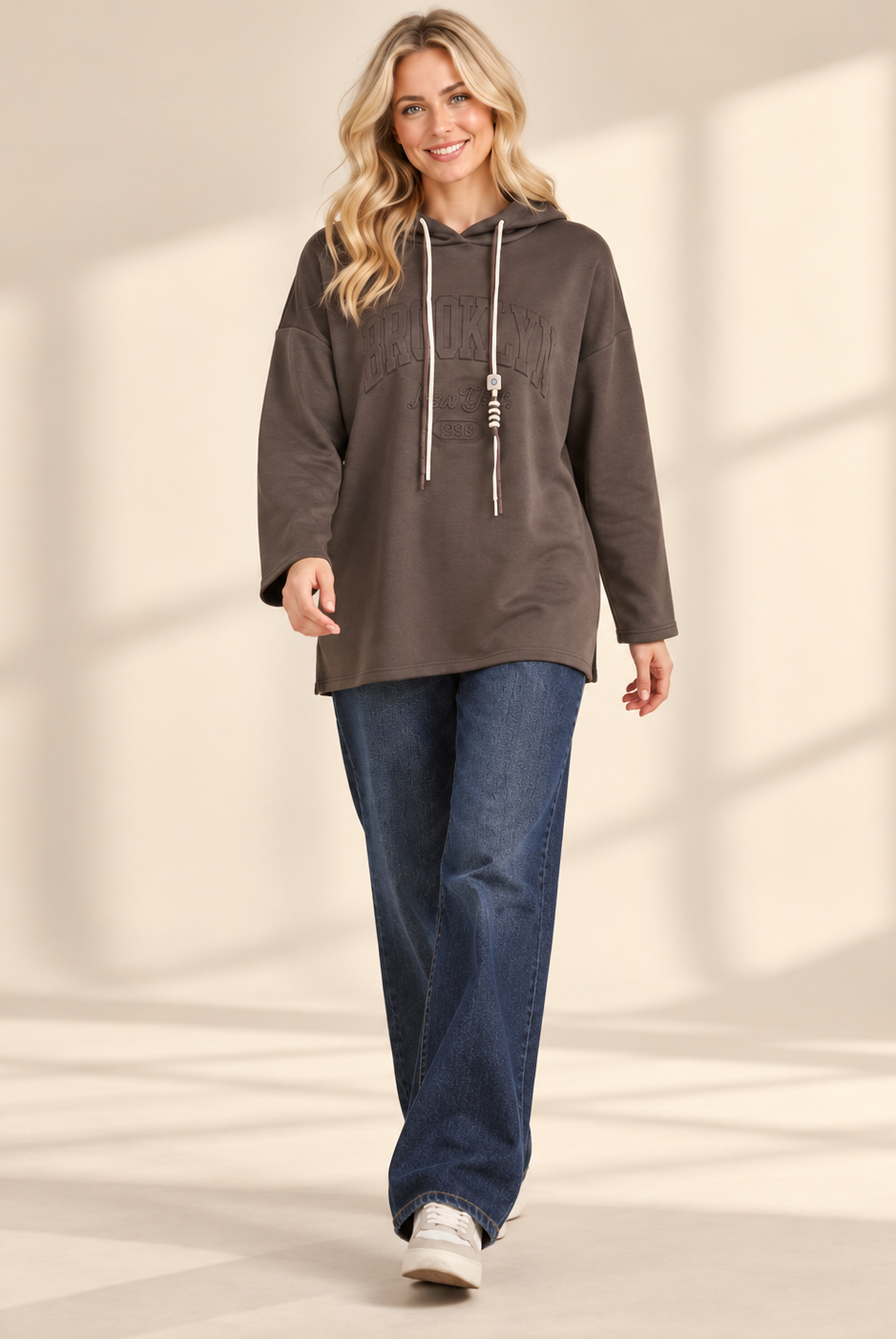 Brun hoodie Brooklyn i längre oversized modell med ton-i-ton-text framtill, huva, kontrasterande dragsnören och långa ärmar med nedhasad axel