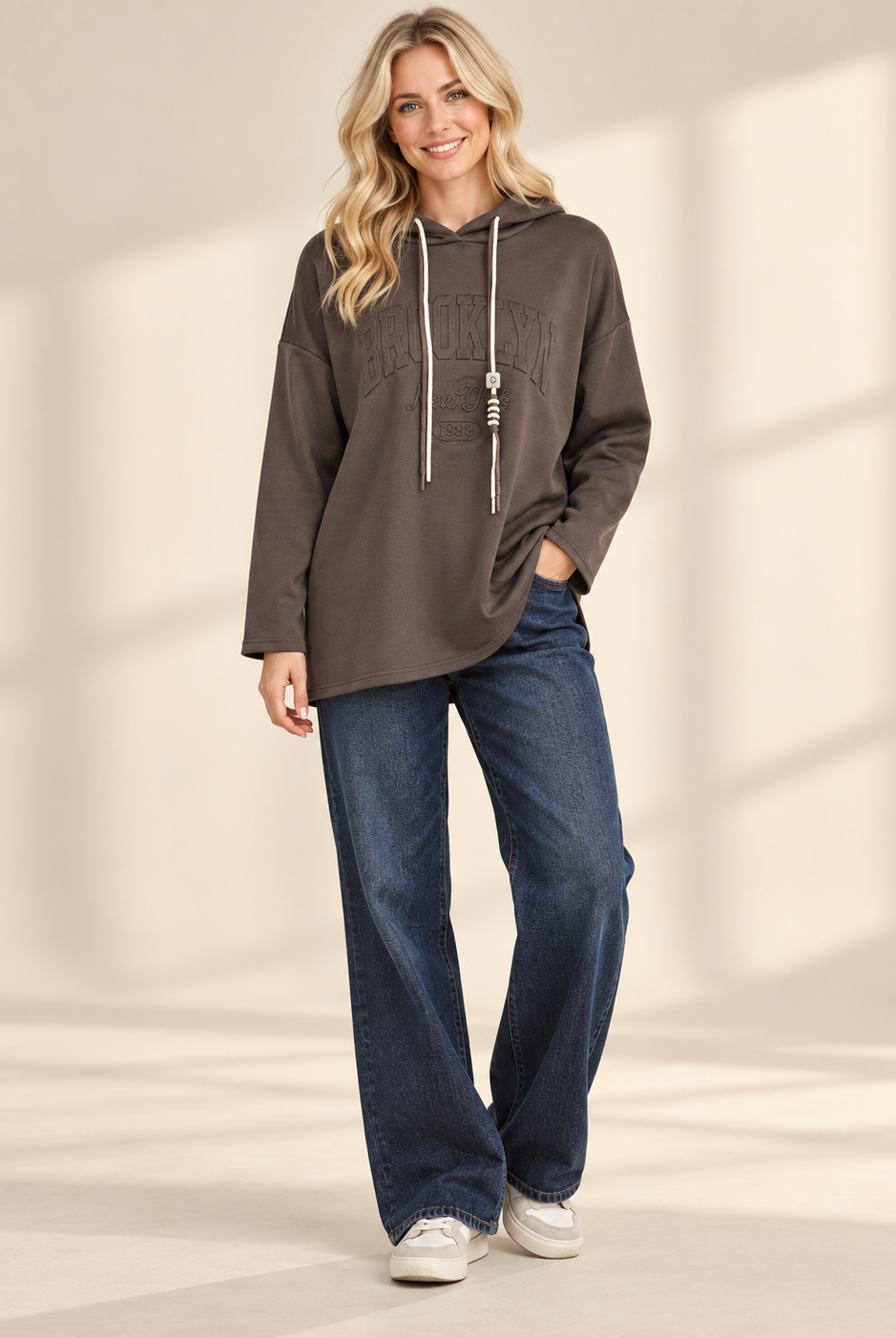 Brun hoodie Brooklyn i längre oversized modell med ton-i-ton-text framtill, huva, kontrasterande dragsnören och långa ärmar med nedhasad axel