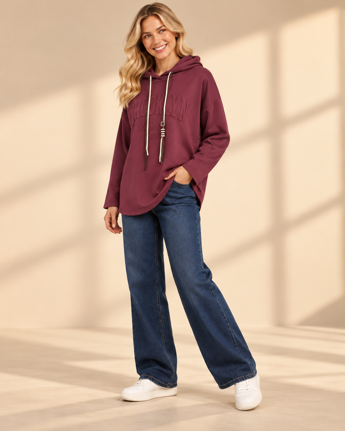 Vinröd hoodie Brooklyn i längre oversized modell med ton-i-ton-text framtill, huva, kontrasterande dragsnören och långa ärmar med nedhasad axel.