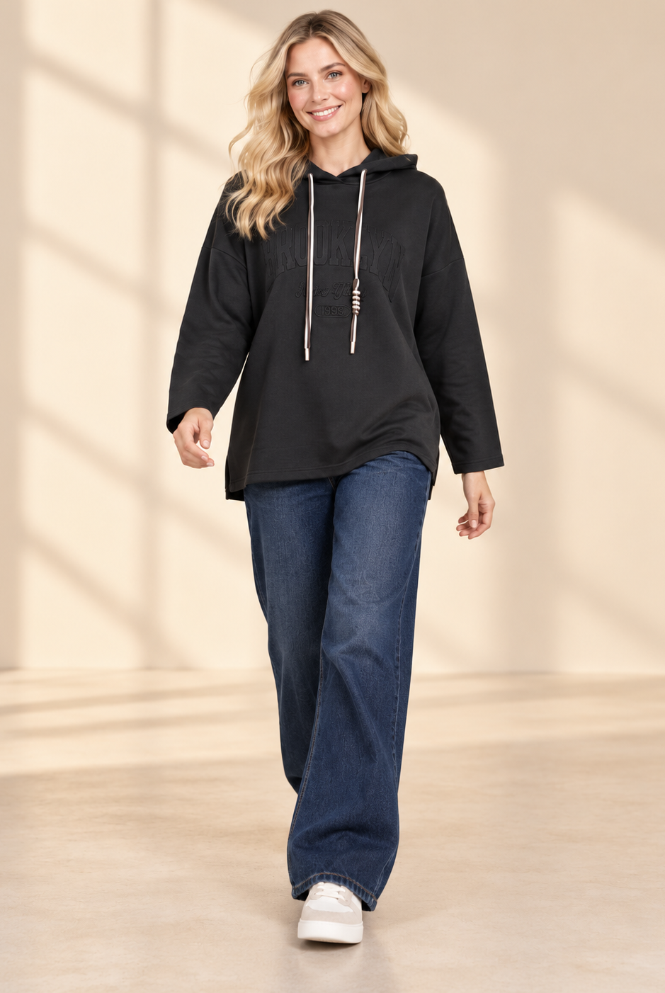 Svart hoodie Brooklyn i längre oversized modell med ton-i-ton-text framtill, huva, kontrasterande dragsnören och långa ärmar med nedhasad axel
