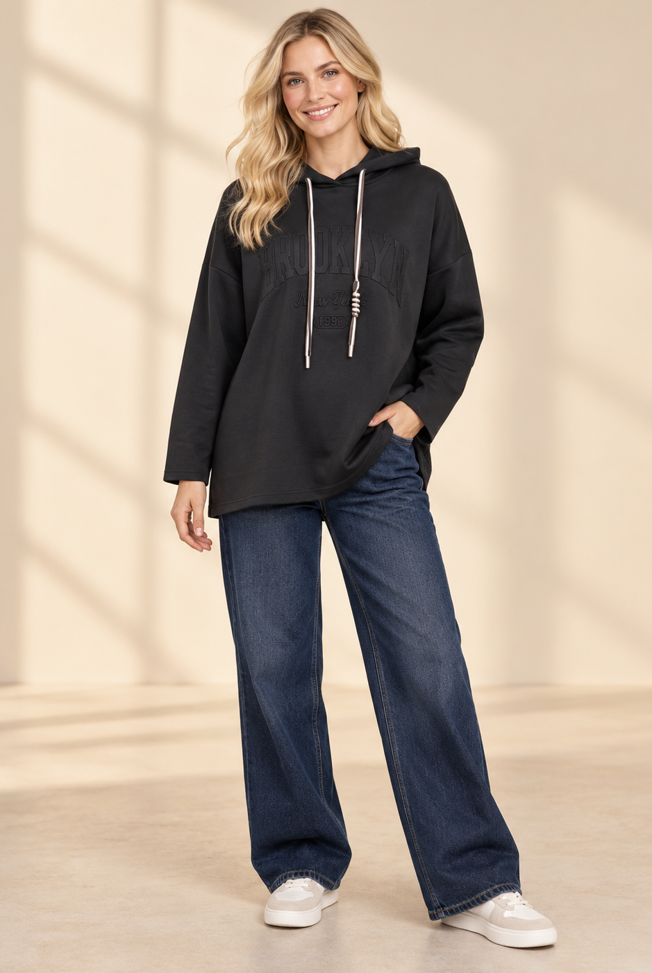 Svart hoodie Brooklyn i längre oversized modell med ton-i-ton-text framtill, huva, kontrasterande dragsnören och långa ärmar med nedhasad axel