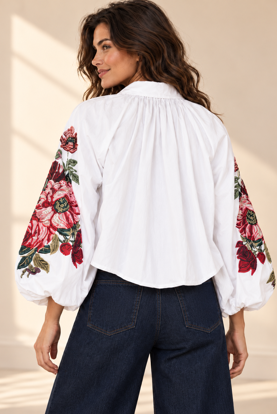 Vit blus Klara med vida ballongärmar, rosa och röda blommotiv, skjortkrage och ledig passform, visad på modell