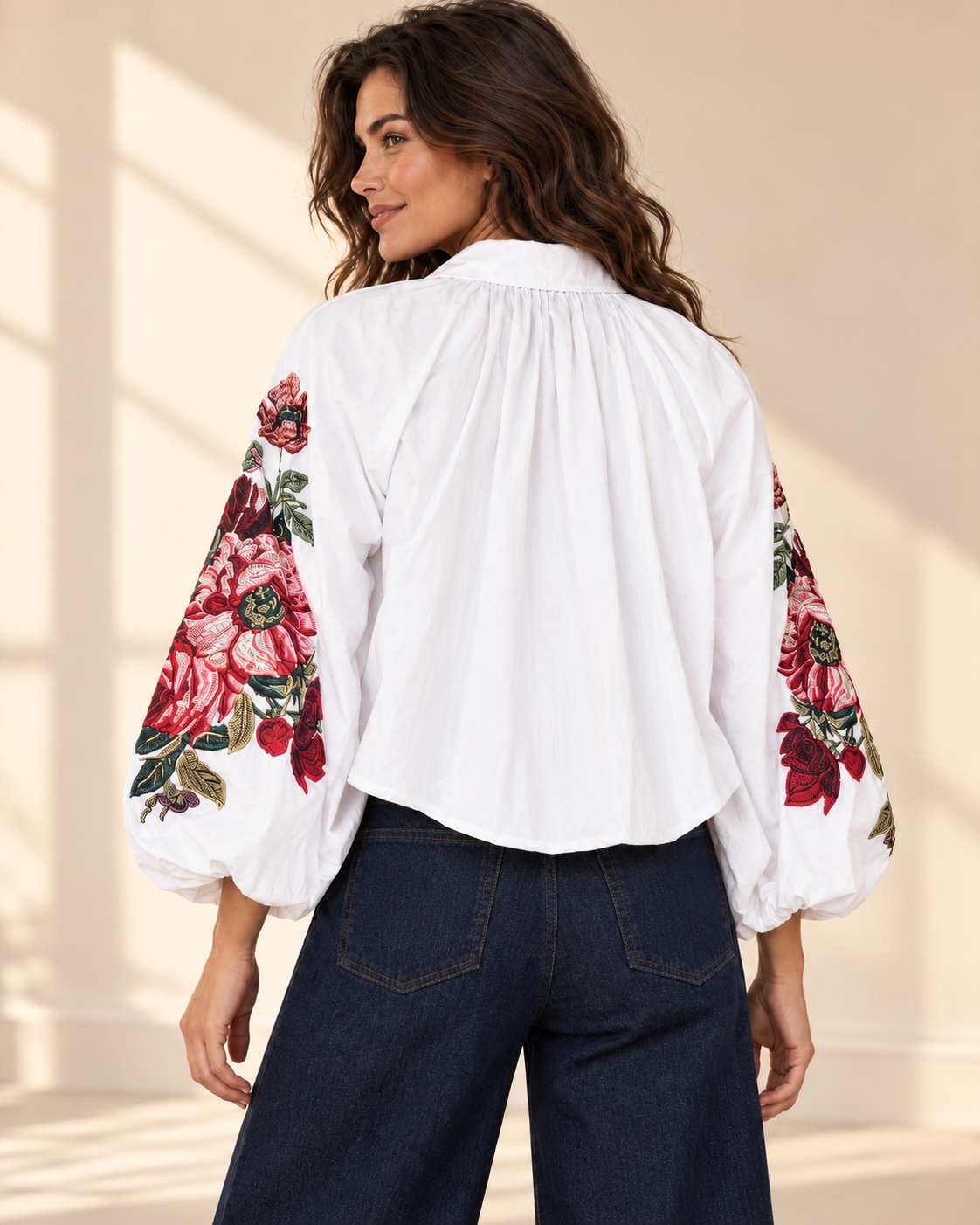 Vit blus Klara med vida ballongärmar, rosa och röda blommotiv, skjortkrage och ledig passform, visad på modell