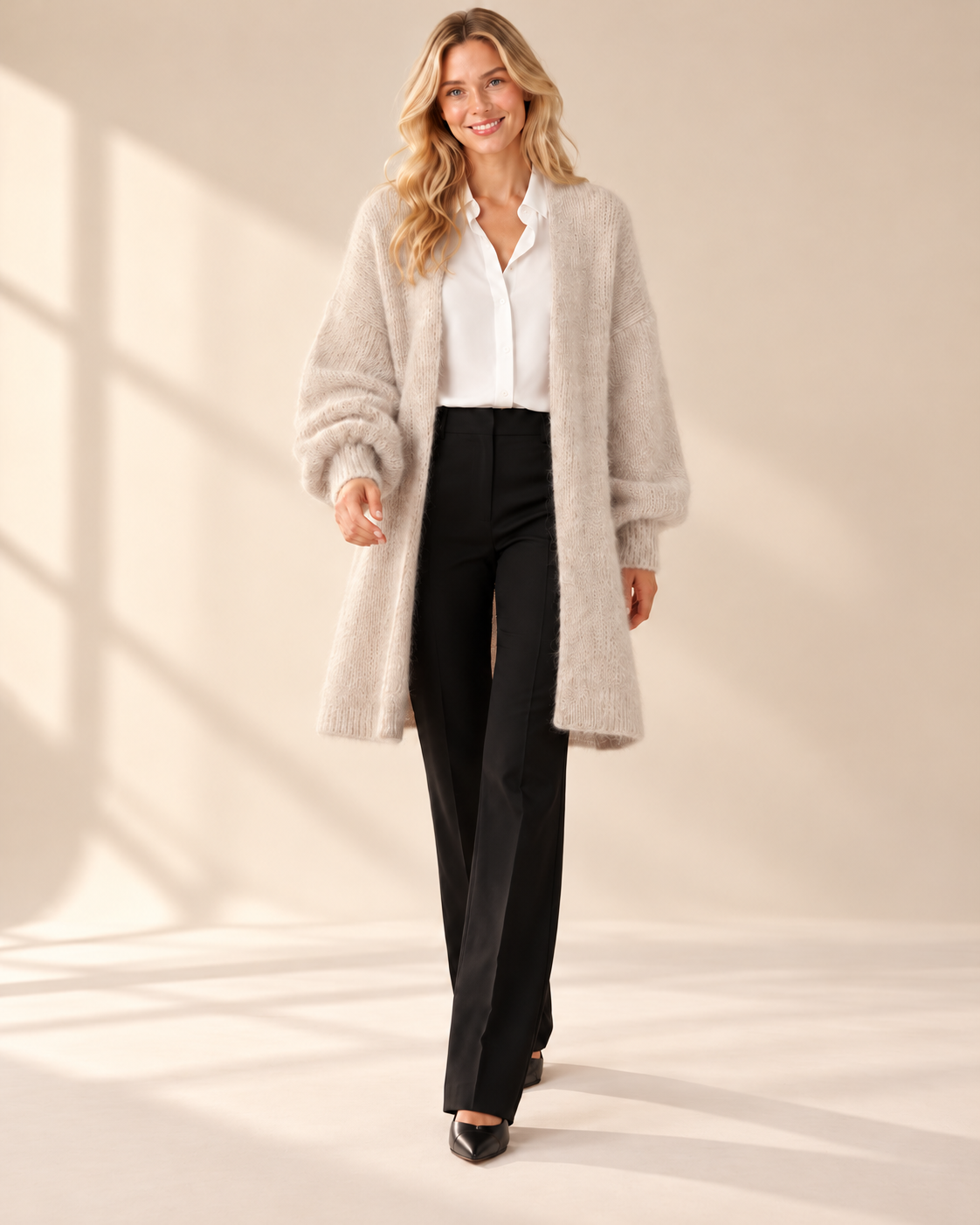 Lång beige mohaircardigan Evelina med luftig stickning, ledig passform och rymliga långa ärmar med ribbstickade muddar, visad på modell.