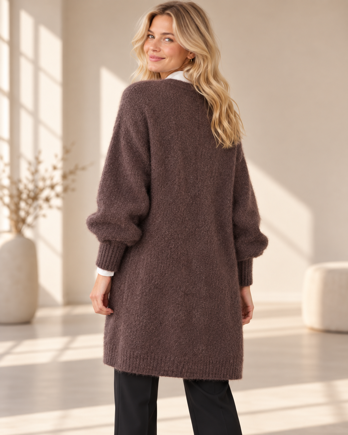 Lång brun mohaircardigan Evelina med öppen front, fluffig stickning och rymliga långa ärmar med ribbstickade muddar, visad på modell.
