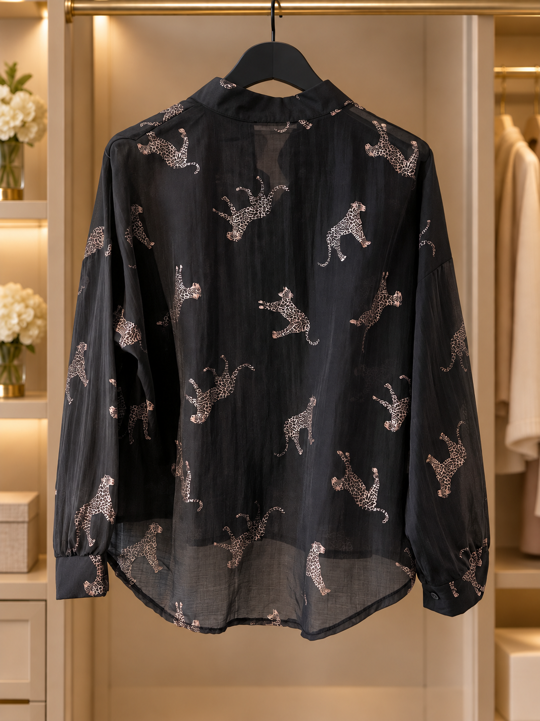 Svart, lätt transparent blus Lollo Gepard med ljusa kattdjursmotiv, långa ärmar med manschetter och rundad nederkant.