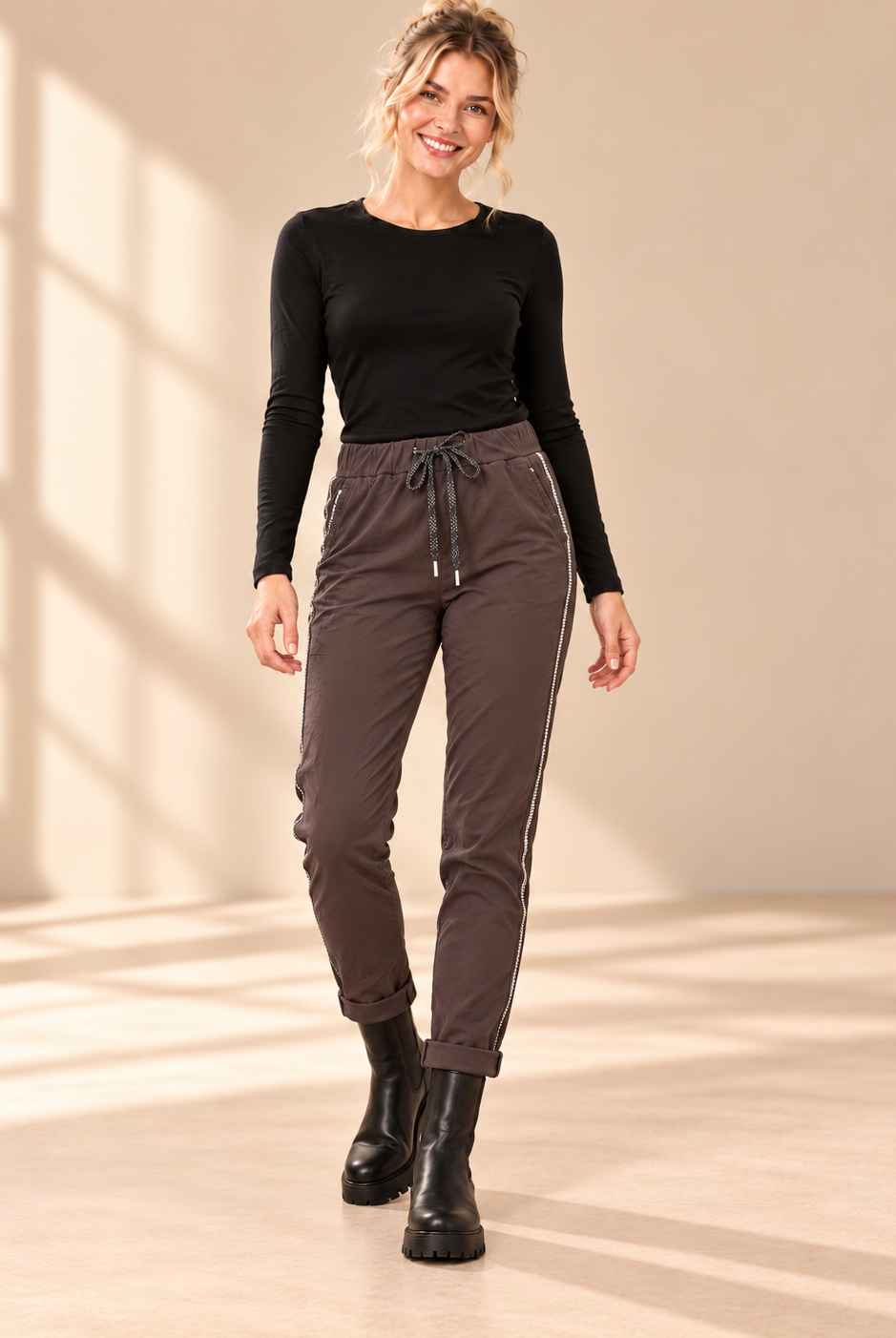 Joggers Diana i brunt med elastisk midja, strassrevär längs sidorna och uppvikta benslut, visade på modell.