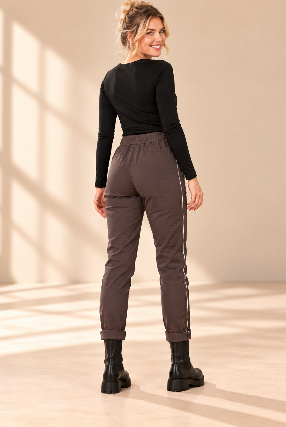 Joggers Diana i brunt med elastisk midja, strassrevär längs sidorna och uppvikta benslut, visade på modell.