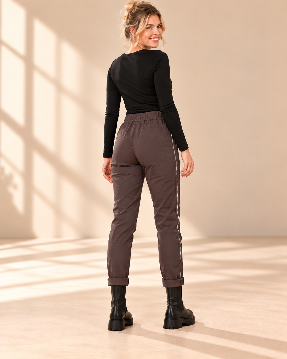 Joggers Diana i brunt med elastisk midja, strassrevär längs sidorna och uppvikta benslut, visade på modell.