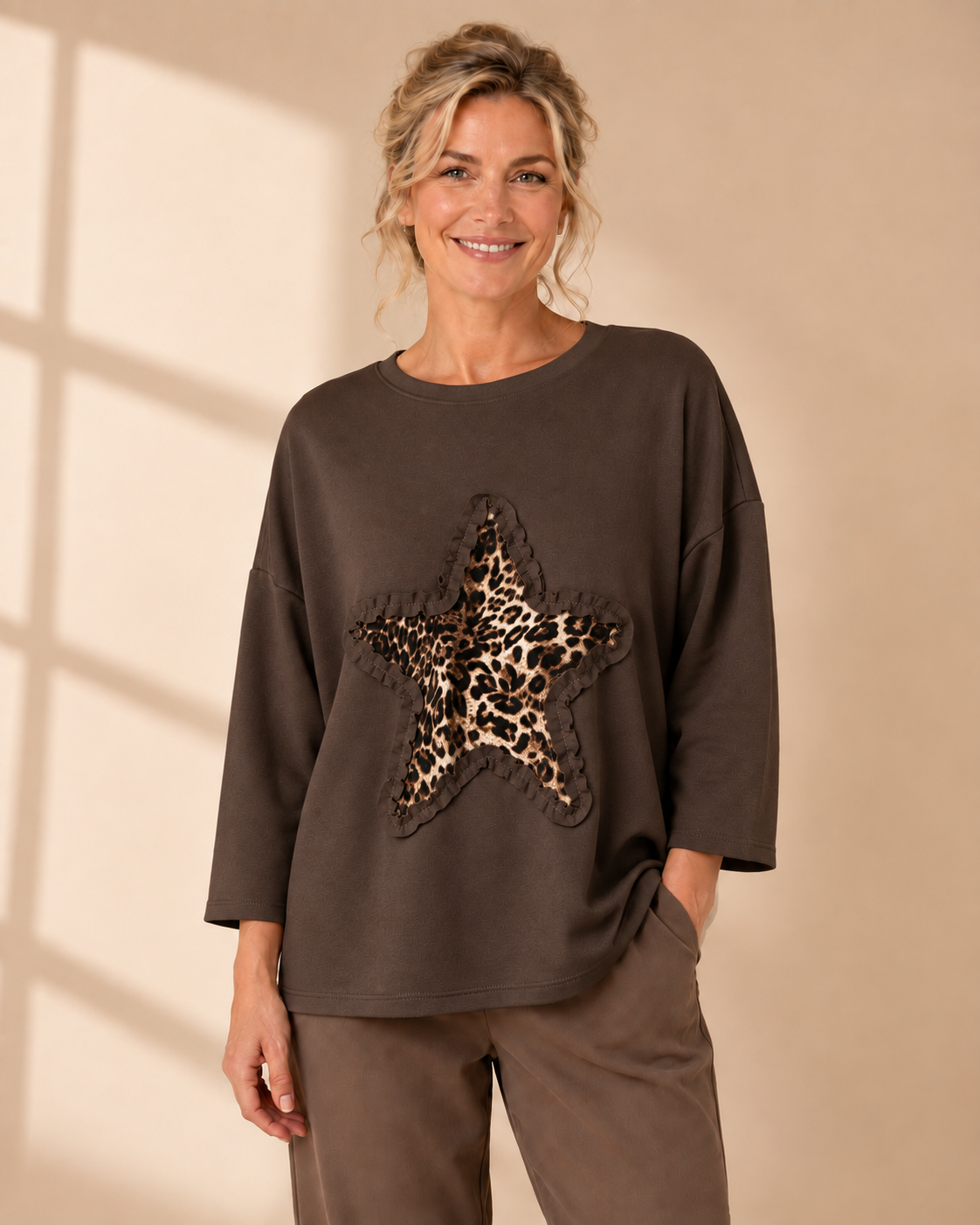 Vit oversize-tröja med leopardmönstrad stjärna och dekorativ volangdetalj framtill.