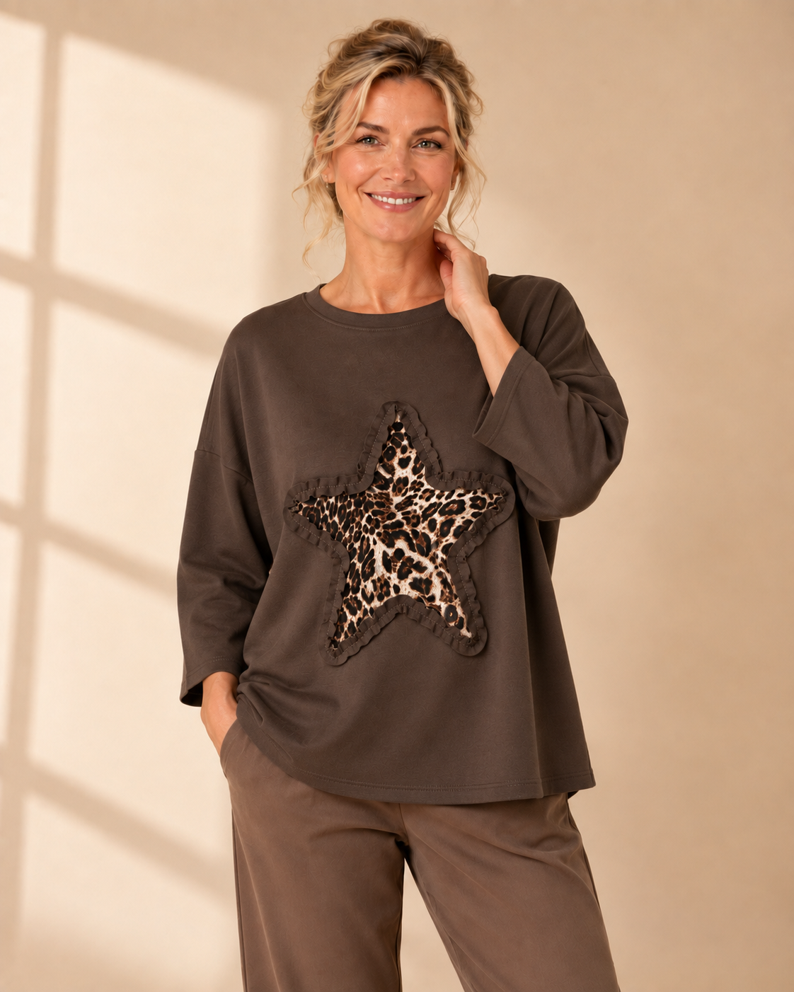 Vit oversize-tröja med leopardmönstrad stjärna och dekorativ volangdetalj framtill.