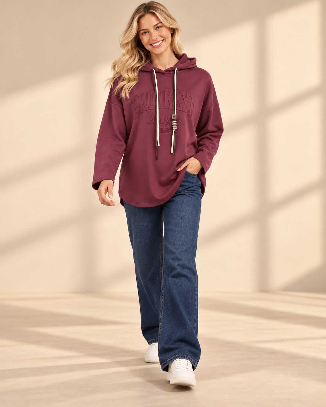 Vinröd hoodie Brooklyn i längre oversized modell med ton-i-ton-text framtill, huva, kontrasterande dragsnören och långa ärmar med nedhasad axel.