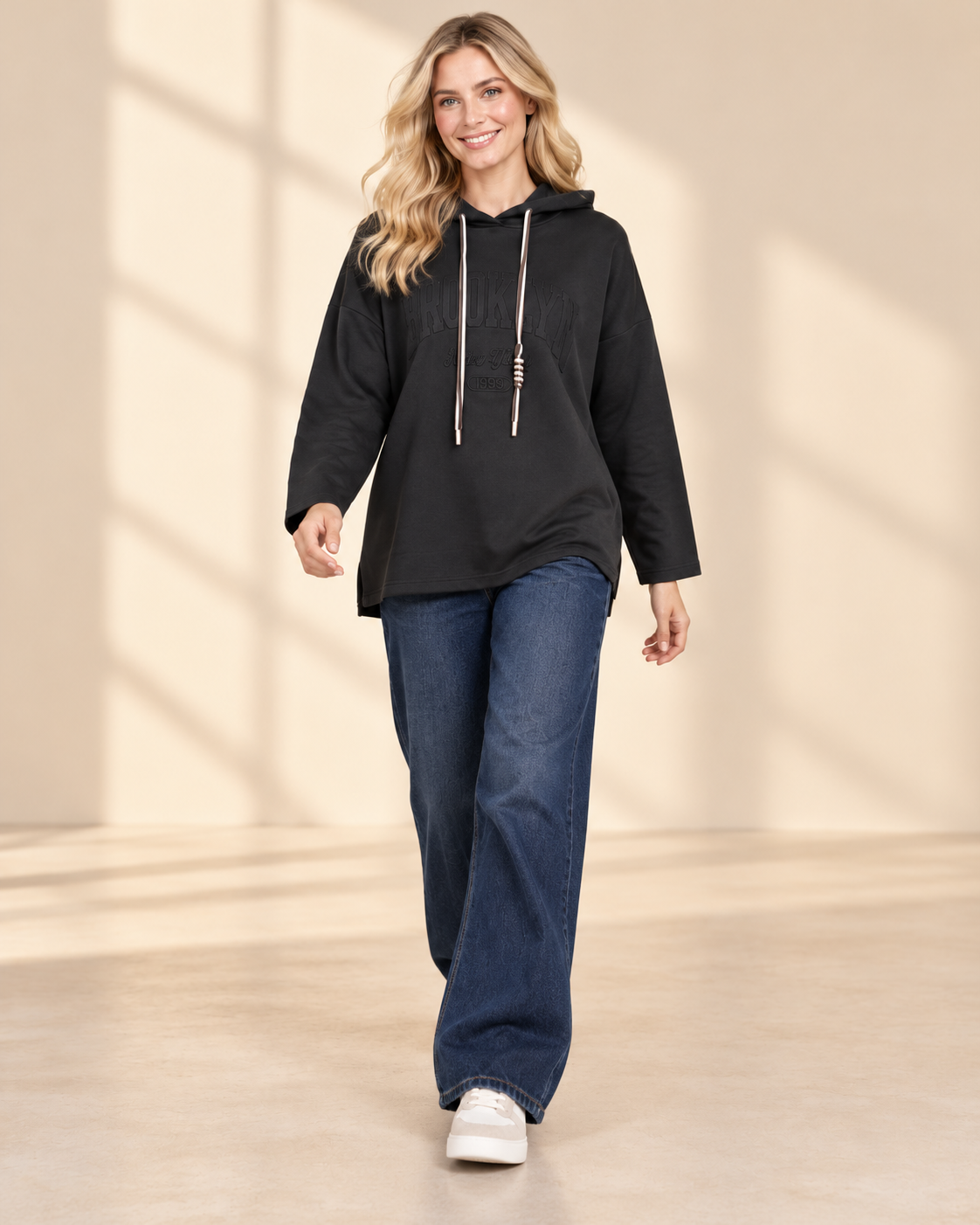 Svart hoodie Brooklyn i längre oversized modell med ton-i-ton-text framtill, huva, kontrasterande dragsnören och långa ärmar med nedhasad axel
