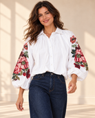 Vit blus Klara med vida ballongärmar, rosa och röda blommotiv, skjortkrage och ledig passform, visad på modell