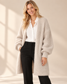 Lång beige mohaircardigan Evelina med luftig stickning, ledig passform och rymliga långa ärmar med ribbstickade muddar, visad på modell.