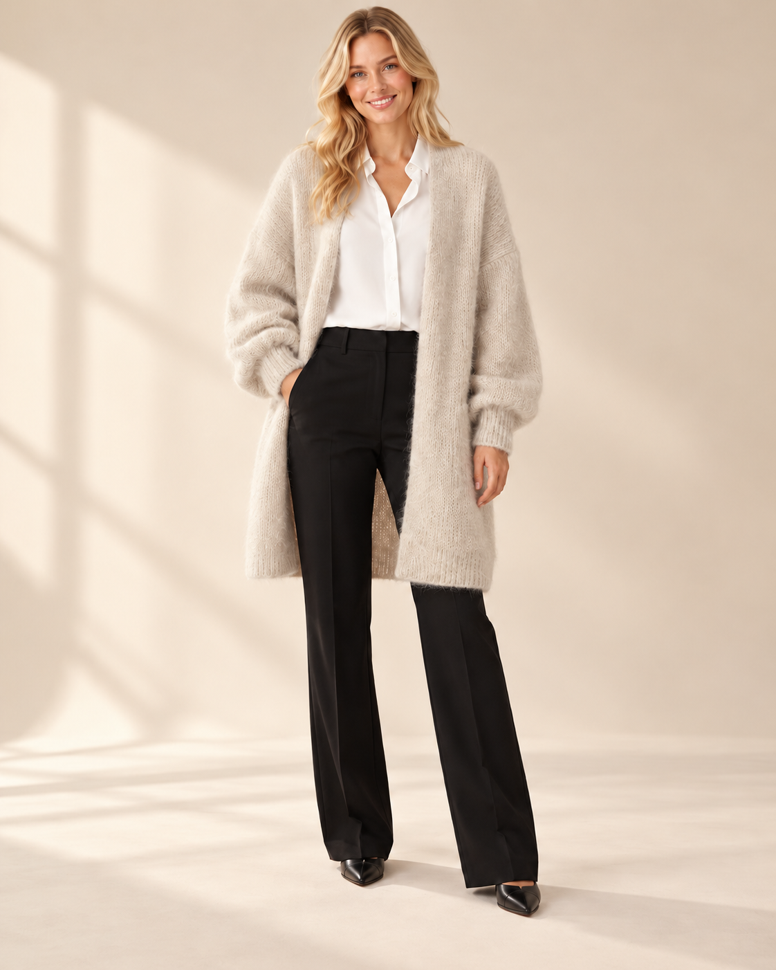 Lång beige mohaircardigan Evelina med luftig stickning, ledig passform och rymliga långa ärmar med ribbstickade muddar, visad på modell.