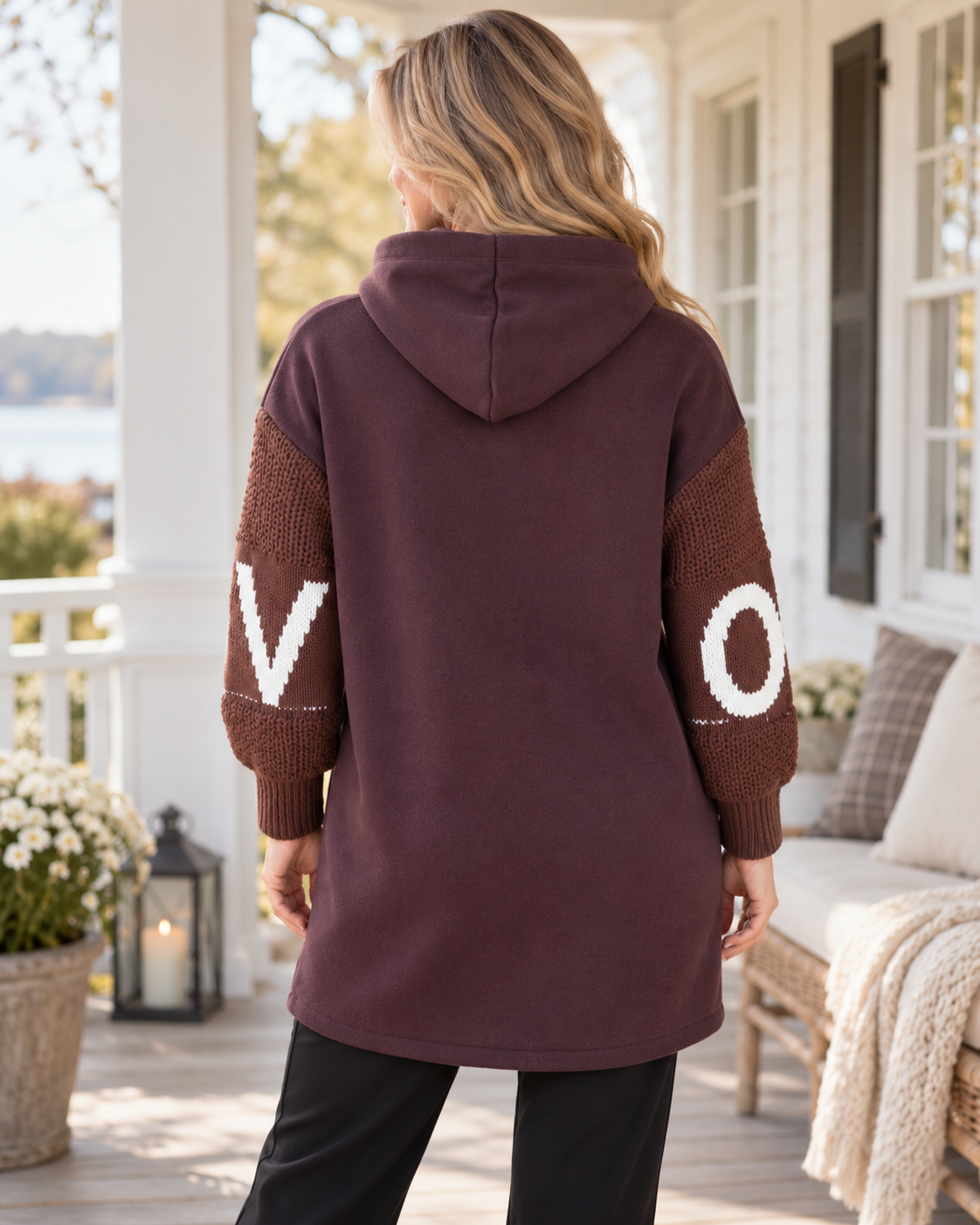 Hoodiejacka LOVE med grovstickade ärmar, vit bokstavsdekor, huva med textband, dragkedja och stora framfickor, visad på modell.