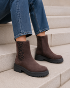 Bottes marron avec élastique léopard et fermeture éclair montrées sur des marches en pierre