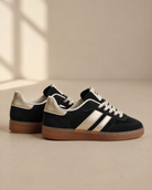 Sorte damesneakers Chicmuse med metalliske detaljer og brun gummisål fra siden