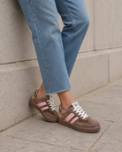Braun-rosafarbene Chicmuse-Sneaker, kombiniert mit geraden Jeans in einer urbanen Umgebung